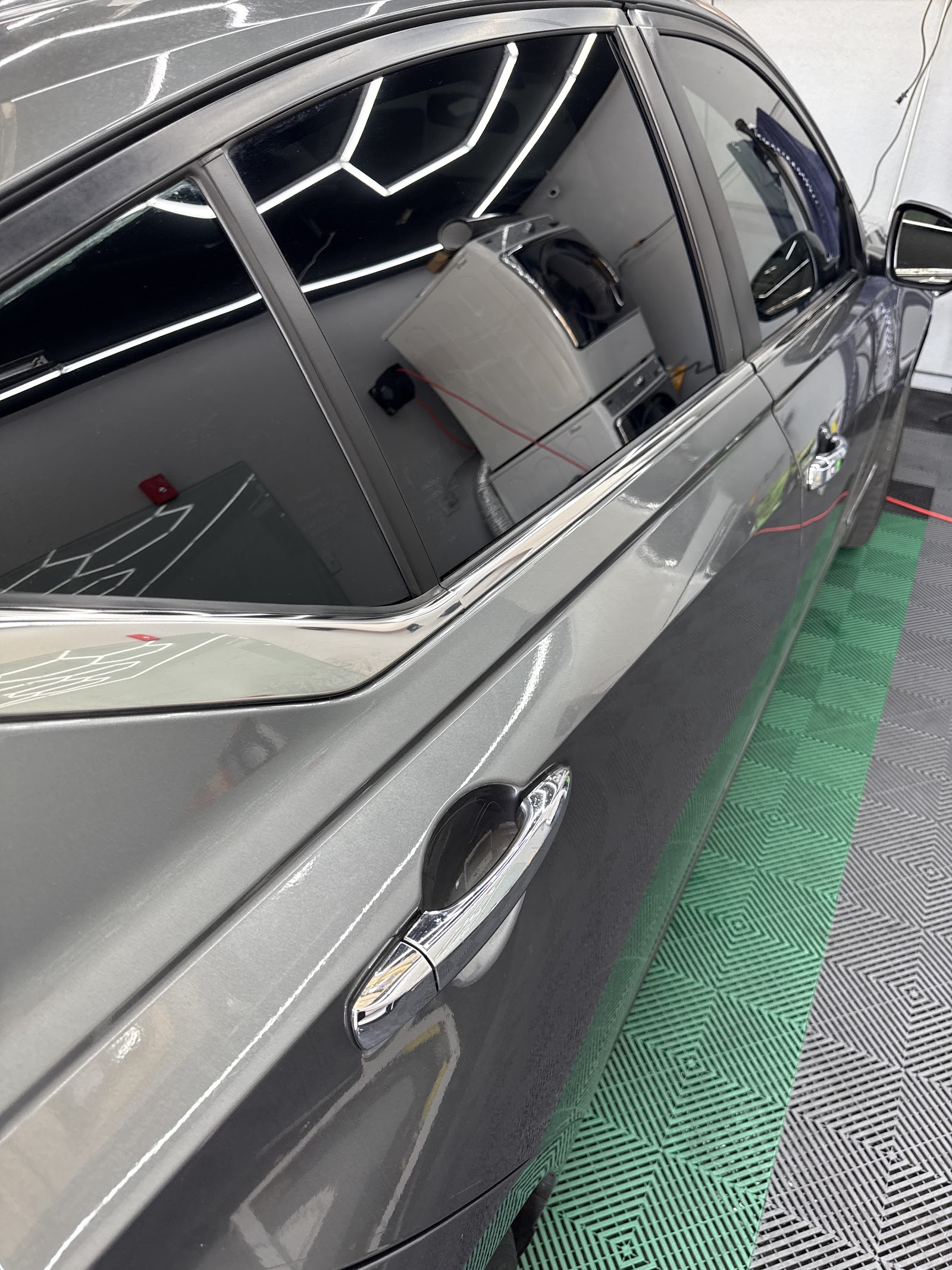 Close-up of a gray sedan with freshly tinted windows on the shop floor