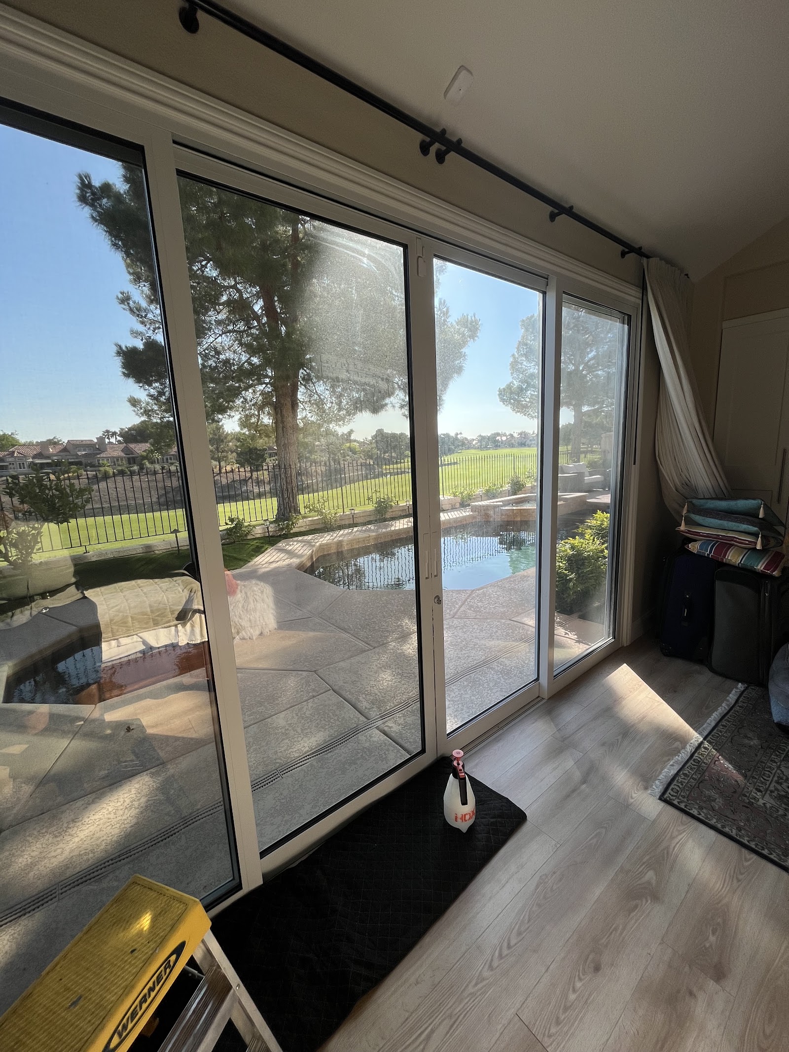 Interior sliding glass door being cleaned with tinting tools and a ladder